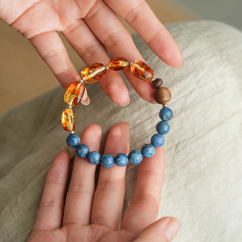 Handmade Blue Crystal, Amber, and Wood Bracelet displayed on a wooden surface – A natural, handcrafted jewelry piece for spiritual balance.