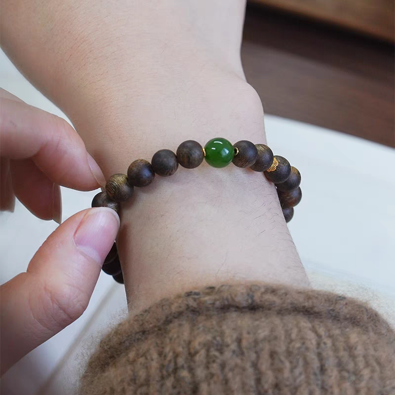 Person wearing Qingyan natural gemstone bracelet with jade and wood beads, showcasing its calming effect.