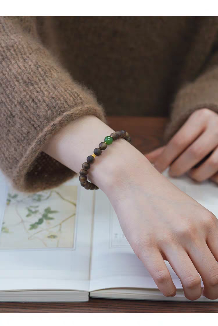 Qingyan handmade bracelet displayed on a light surface, with jade and wooden beads for harmony and tranquility.