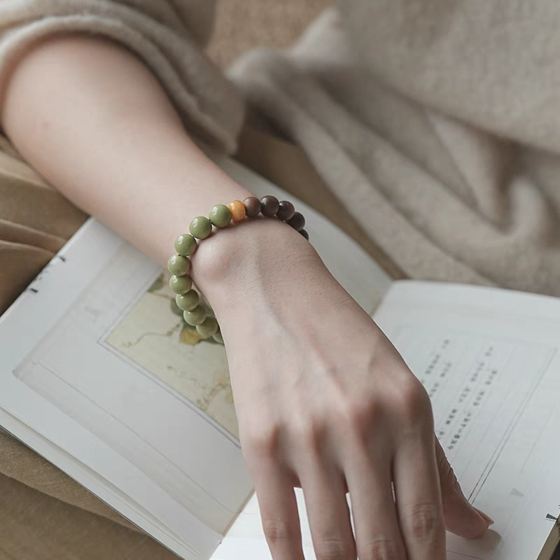 Yanyan Green Aventurine Wood and Amber Healing Bracelet on Open Book – Calming Natural Jewelry for Stress Relief