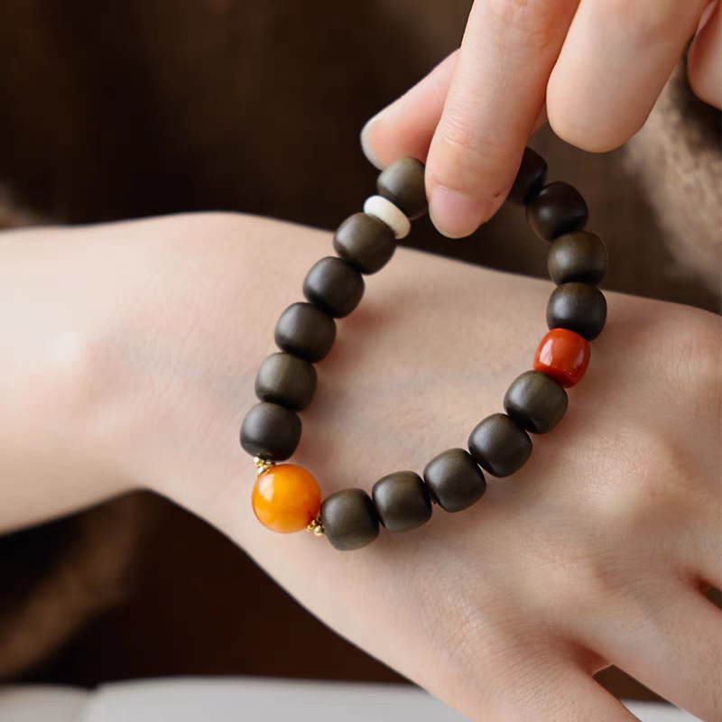 Hand holding Chanyin handmade healing bracelet with black obsidian and carnelian beads, showcasing the 18k gold accents.