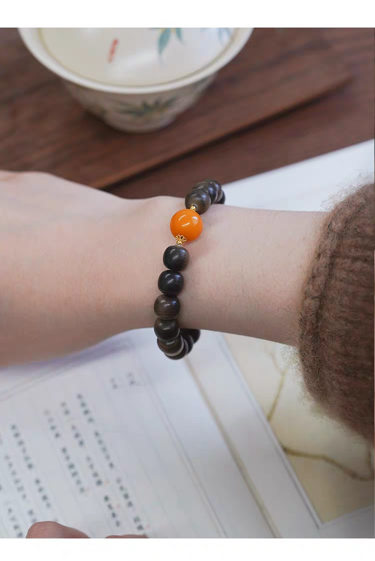 Chanyin black obsidian and carnelian healing bracelet placed on table next to a decorative jewelry box with 18k gold accents.