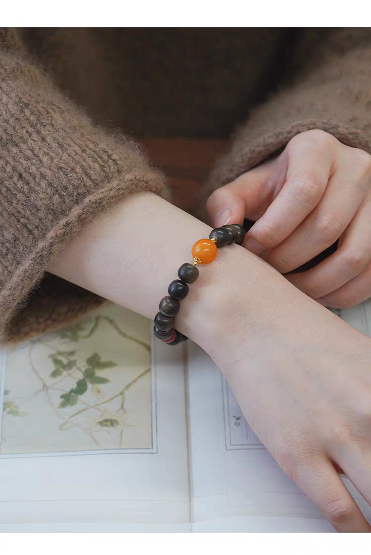 Close-up of Chanyin natural gemstone healing bracelet with black obsidian, carnelian beads, and 18k gold accents on white background.
