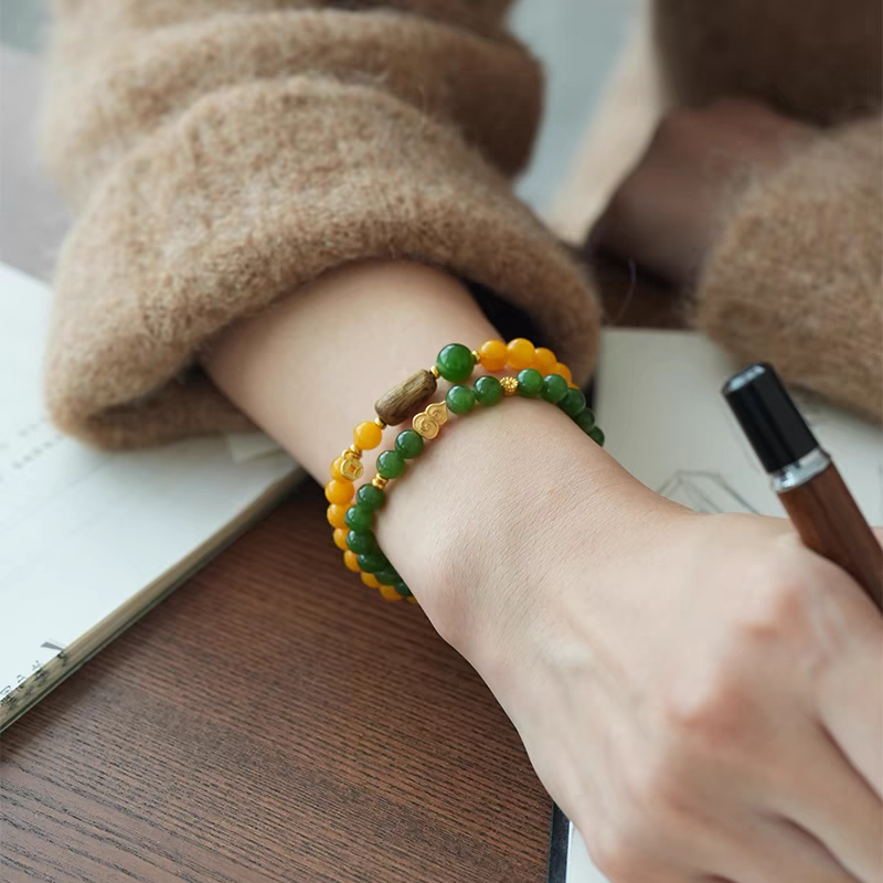 Wrist shot of Yanyan handmade bracelet with yellow jade, green aventurine, and wooden beads on a hand.