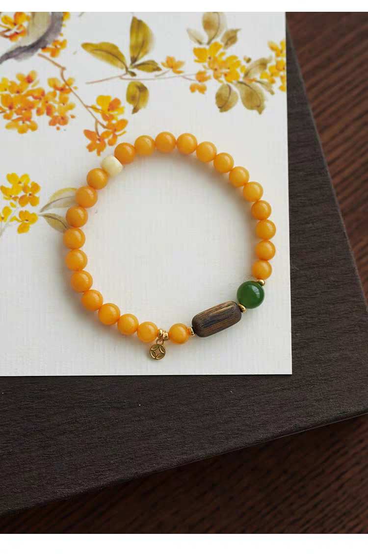 Flat lay image of Yanyan bracelet featuring yellow jade and green aventurine gemstones with a wooden bead, perfect for energy balance.